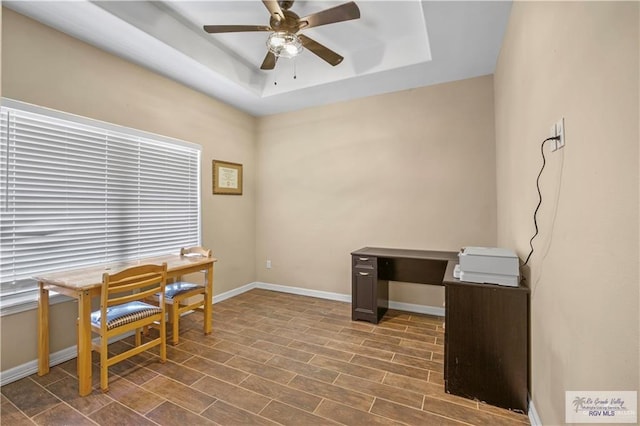 office space with ceiling fan and a tray ceiling