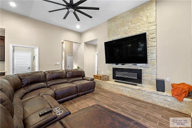 living room with ceiling fan and a stone fireplace