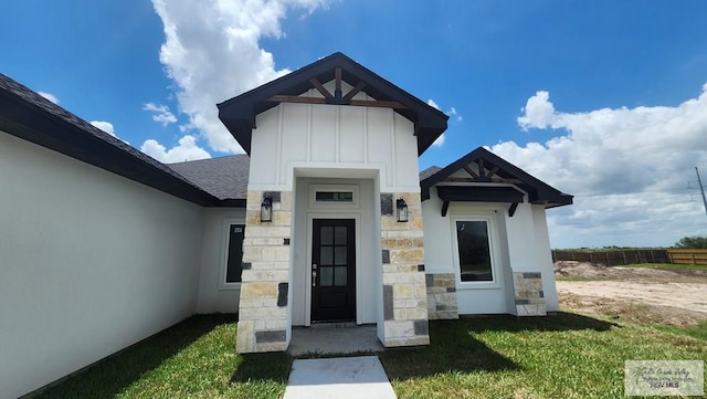 1418 Stirrup Cir, San Benito, TX 78586 - view of exterior entry featuring board and batten siding, stone siding, and a shingled roof