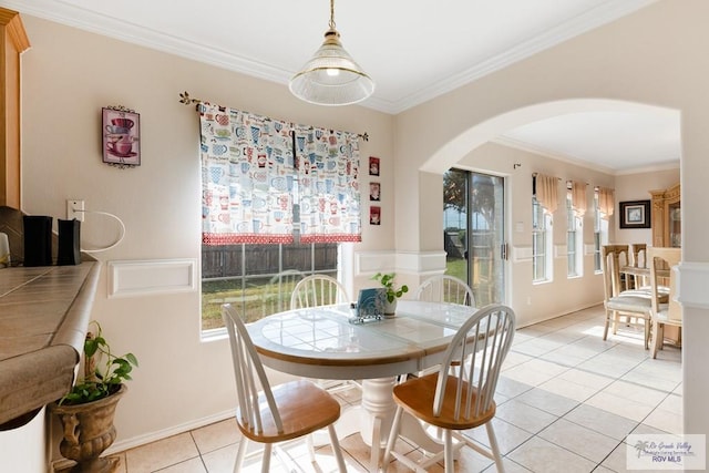 dining space featuring a wealth of natural light, arched walkways, ornamental molding, and light tile patterned flooring