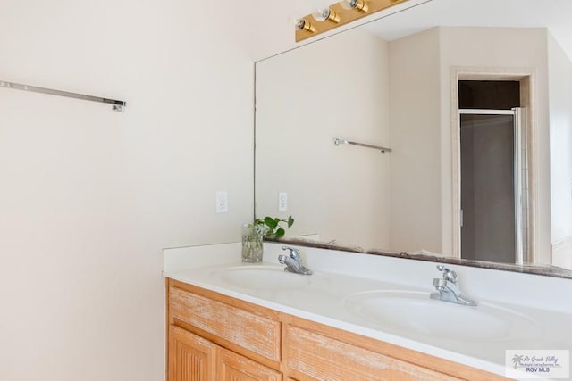 bathroom featuring a sink, a shower with shower door, and double vanity