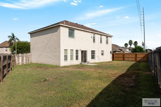 rear view of house featuring a lawn and a fenced backyard