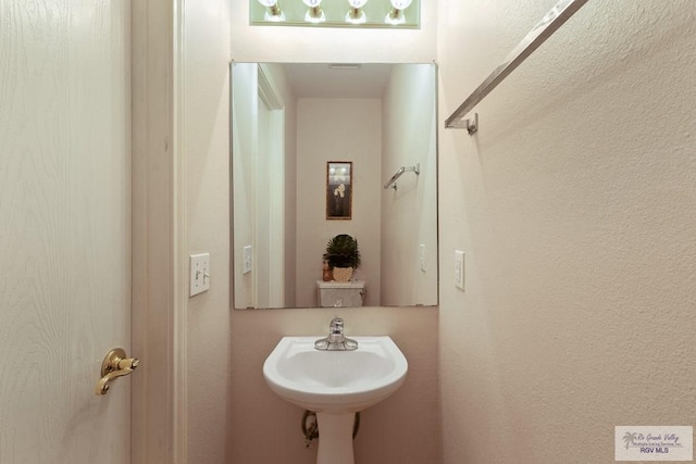 bathroom featuring a sink and a textured wall