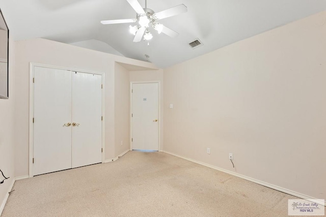 unfurnished bedroom featuring visible vents, ceiling fan, vaulted ceiling, a closet, and light colored carpet