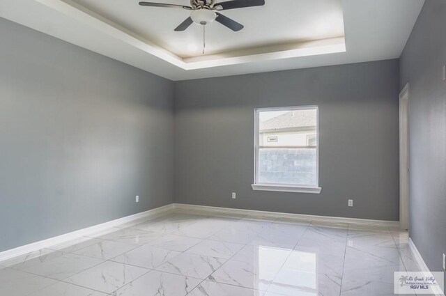 spare room with a tray ceiling and ceiling fan