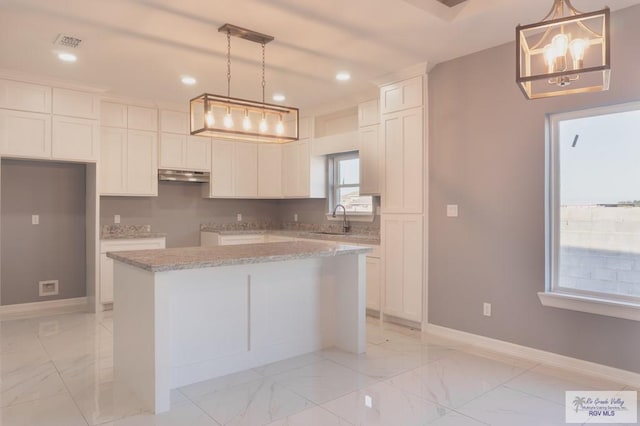 kitchen featuring white cabinets, decorative light fixtures, a kitchen island, and sink