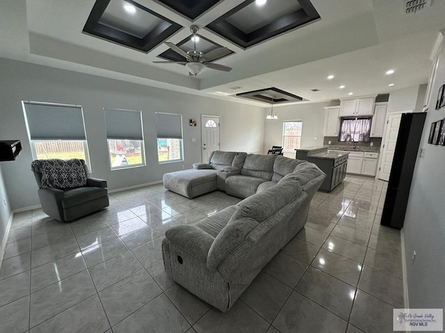 tiled living area featuring visible vents, baseboards, ceiling fan, recessed lighting, and a tray ceiling