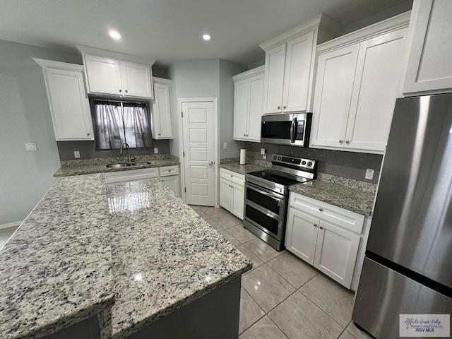 kitchen featuring white cabinets, light stone countertops, a sink, stainless steel appliances, and recessed lighting