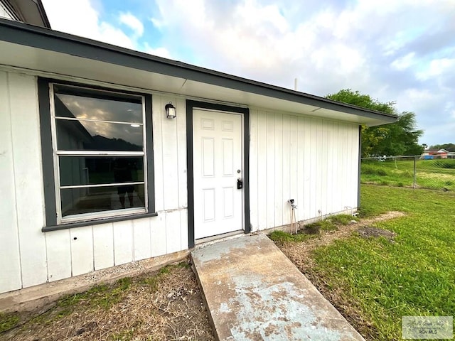property entrance featuring a yard and fence