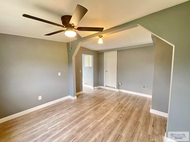 spare room featuring light wood finished floors, baseboards, and ceiling fan