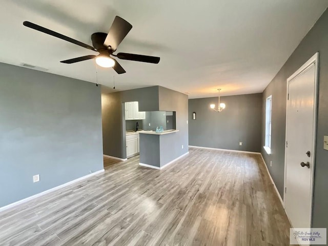 unfurnished living room with light wood finished floors, baseboards, visible vents, and ceiling fan with notable chandelier