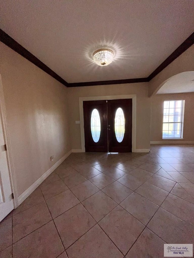 foyer with crown molding and light tile patterned flooring