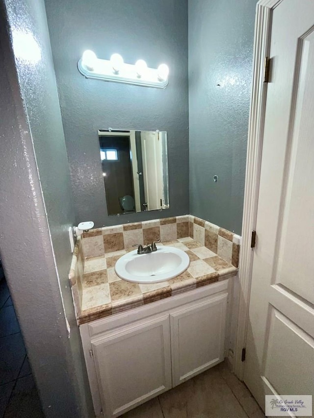 bathroom with vanity, toilet, and backsplash