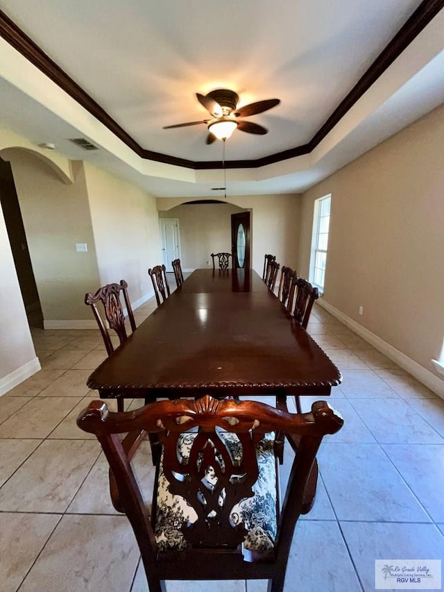 tiled dining room featuring ceiling fan, ornamental molding, and a tray ceiling