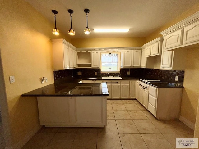 kitchen with kitchen peninsula, sink, hanging light fixtures, light tile patterned floors, and white cabinetry