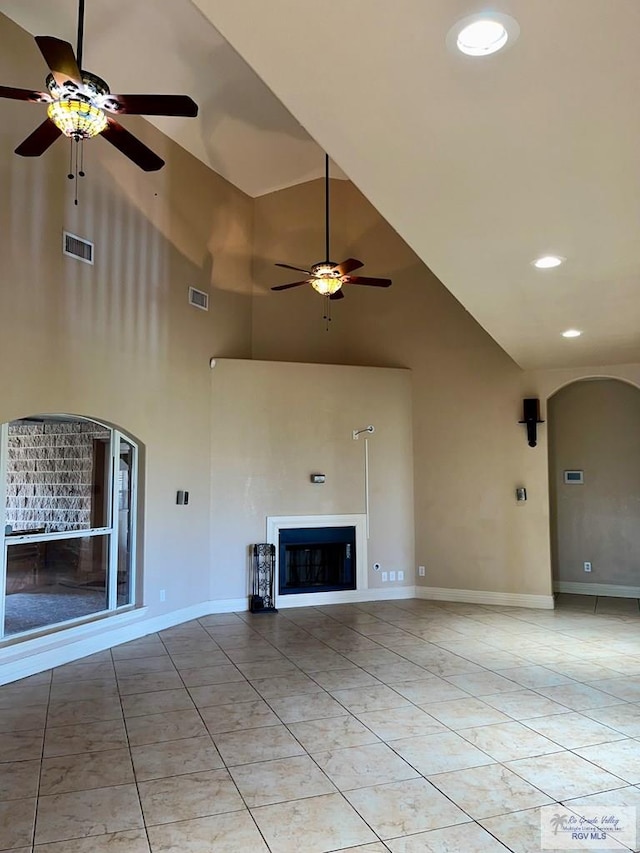 unfurnished living room with ceiling fan, high vaulted ceiling, and light tile patterned flooring