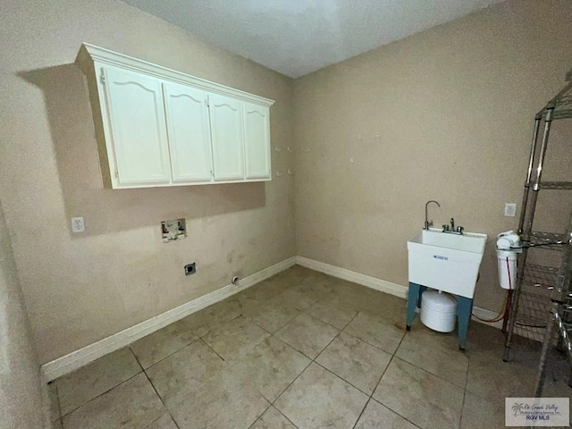 clothes washing area featuring electric dryer hookup, hookup for a washing machine, light tile patterned flooring, and cabinets