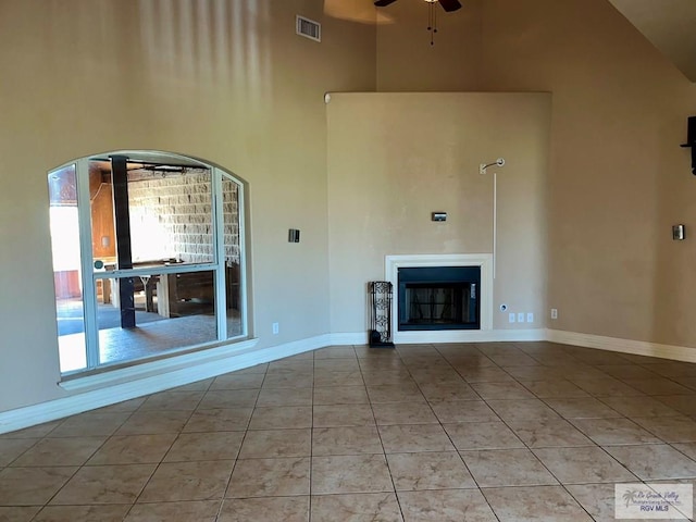 unfurnished living room featuring light tile patterned floors, a towering ceiling, and ceiling fan