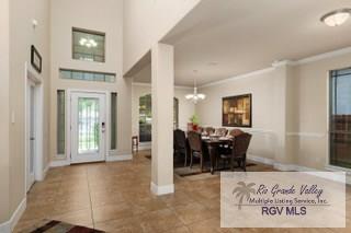 entryway with ornamental molding, tile patterned floors, plenty of natural light, and a notable chandelier