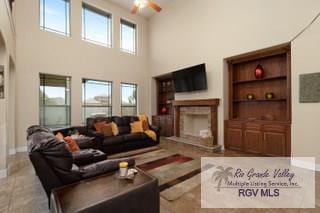 living room with ceiling fan, a fireplace, a high ceiling, and built in shelves