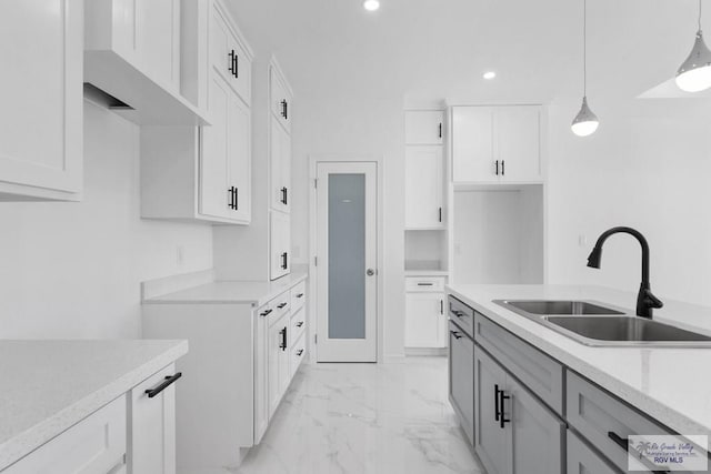 kitchen featuring decorative light fixtures, white cabinetry, and sink