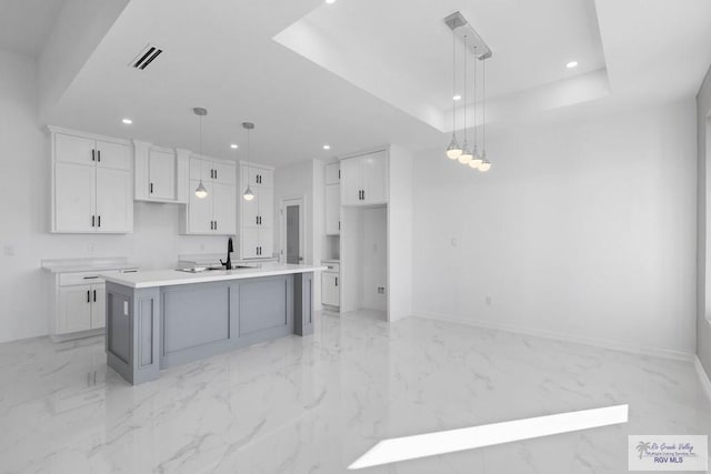 kitchen with a kitchen island with sink, sink, white cabinets, and pendant lighting