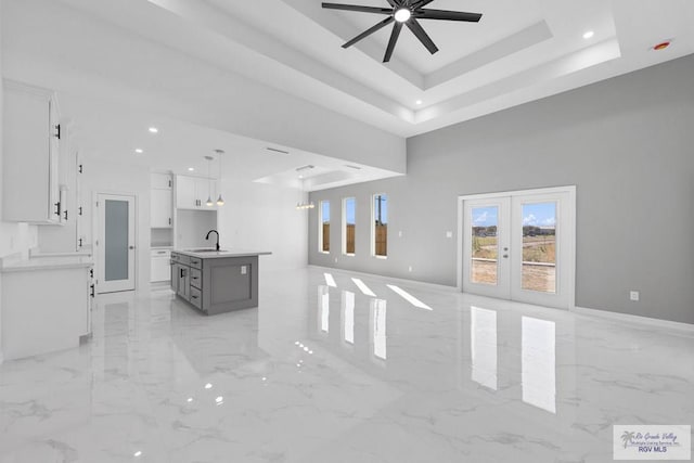 living room featuring french doors, a tray ceiling, ceiling fan, and sink