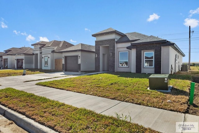 prairie-style home featuring central air condition unit, a front yard, and a garage