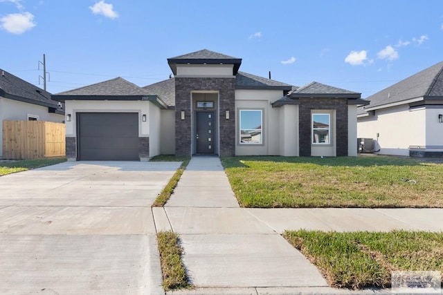 prairie-style home with a front yard, central AC unit, and a garage