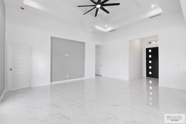 spare room featuring ceiling fan, a raised ceiling, and a high ceiling