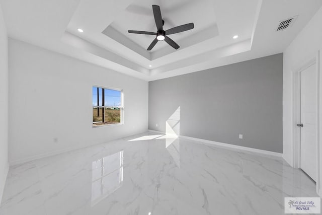 unfurnished room featuring ceiling fan and a tray ceiling