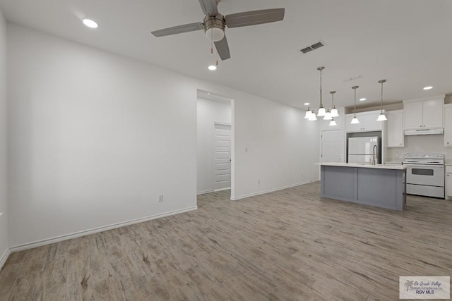 kitchen with white appliances, white cabinets, light hardwood / wood-style floors, decorative light fixtures, and a kitchen island