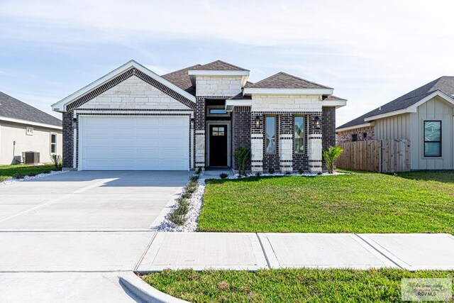 8801 Swan Lake Dr # 24, Harlingen, TX 78552 - view of front facade featuring driveway, a garage, fence, central air condition unit, and a front lawn