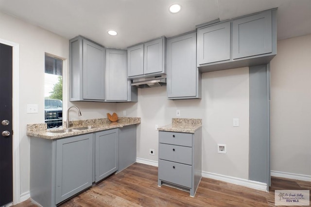 kitchen with gray cabinetry, light stone countertops, dark hardwood / wood-style flooring, and sink