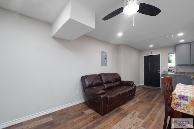 living room featuring electric panel, ceiling fan, sink, and dark hardwood / wood-style floors