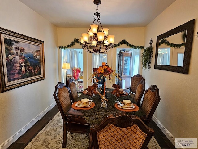 dining area with dark hardwood / wood-style flooring and a chandelier