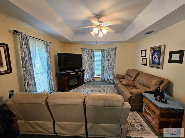 living room featuring a tray ceiling and ceiling fan