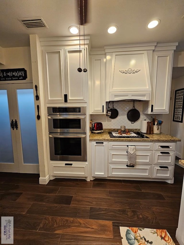 kitchen featuring double oven, dark wood-type flooring, custom range hood, and gas cooktop