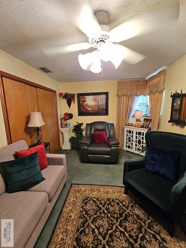 carpeted living room featuring ceiling fan and a textured ceiling