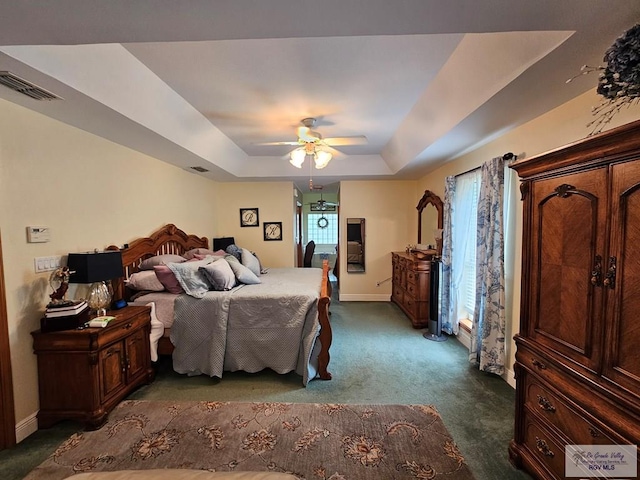 carpeted bedroom featuring a raised ceiling and ceiling fan