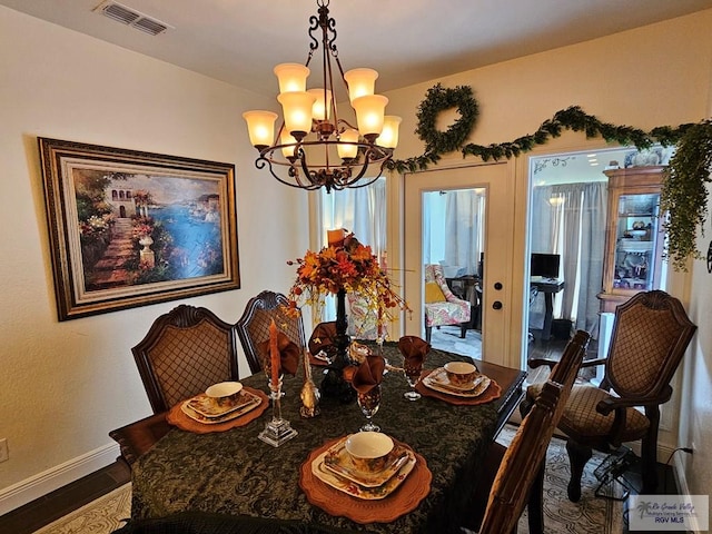 dining room featuring french doors, dark hardwood / wood-style flooring, plenty of natural light, and a notable chandelier