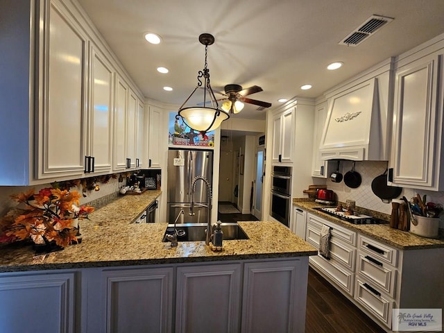 kitchen featuring kitchen peninsula, backsplash, dark hardwood / wood-style flooring, stainless steel appliances, and pendant lighting