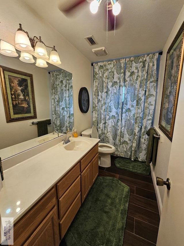 bathroom with a shower with curtain, vanity, ceiling fan, hardwood / wood-style flooring, and toilet