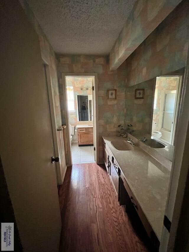 35 Alvarado Ave, Rancho Viejo, TX 78575 - bathroom featuring toilet, vanity, a textured ceiling, and wood finished floors