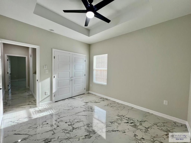 406 Valle Alto Dr, Los Fresnos, TX 78566 - unfurnished bedroom with light marble finish flooring, a tray ceiling, a closet, and a ceiling fan