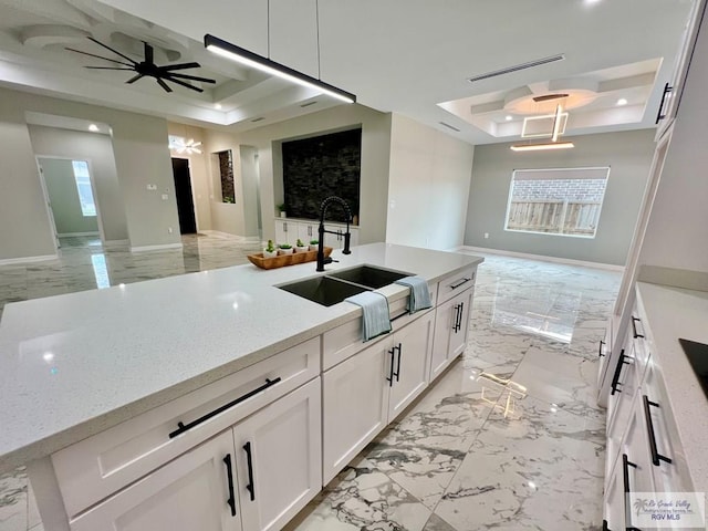 406 Valle Alto Dr, Los Fresnos, TX 78566 - kitchen with open floor plan, a tray ceiling, light marble finish floors, white cabinets, and a ceiling fan