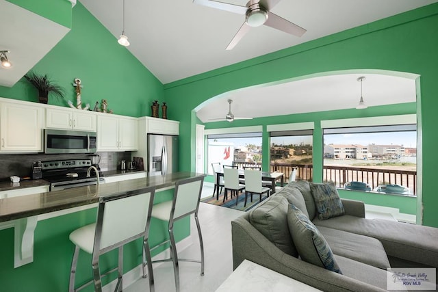 kitchen featuring appliances with stainless steel finishes, white cabinets, hanging light fixtures, a breakfast bar area, and decorative backsplash