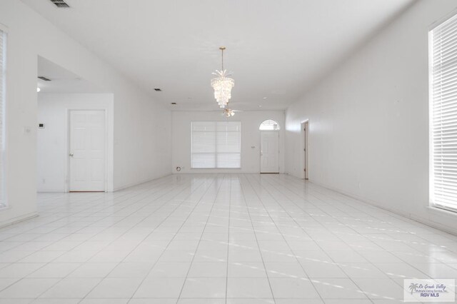 tiled empty room featuring a notable chandelier