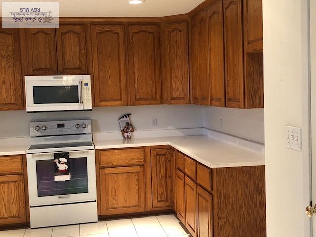 kitchen featuring white appliances and light tile patterned flooring