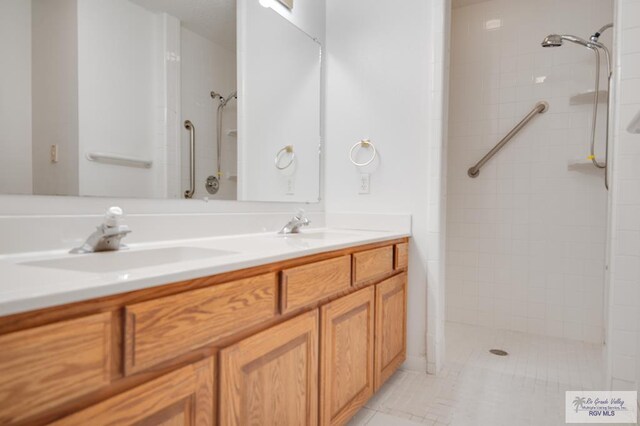 bathroom with tile patterned floors, vanity, and a tile shower